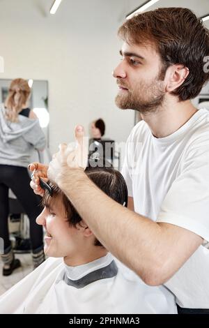 Barber talking to caucasian man while sitting in chair Stock Photo