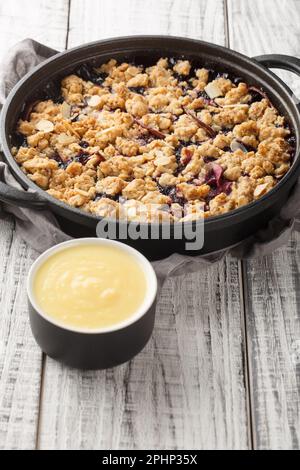 Swedish pie Smulpaj baked with apples and blueberries close-up in a pan on the table. Vertical Stock Photo
