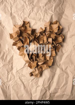 Heart shape made from recycled paper packaging material on a crushed recycled paper background Stock Photo