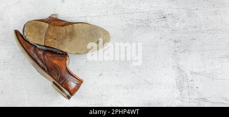 Top down view, worn classic dark brown brogue shoes on white board. Wide banner with space for text right Stock Photo