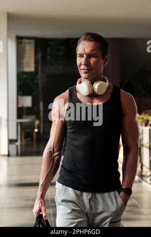 Fit positive mature man with headphones hurrying to gym in the morning Stock Photo