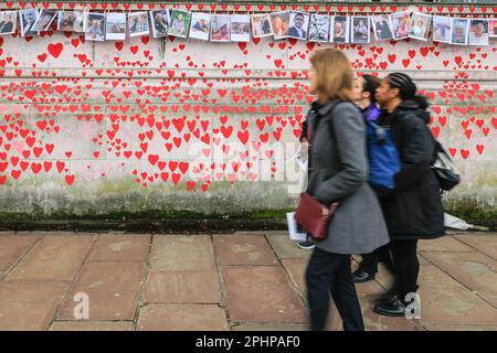 London, UK. 29th Mar, 2023. Bereaved families, friends, colleagues and others remembering the victims of the coronavirus have come to mark the anniversary of the National Covid Memorial Wall along the River Thames today, organised by Friends of the Wall. Pictures of hundreds of victims are displayed in a long line along the wall.The wall was first created in 2021 and its anniversary is on Wednesday 29th March. Credit: Imageplotter/Alamy Live News Stock Photo