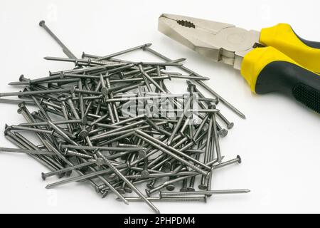 Metal nails, yellow pliers on a white background Stock Photo