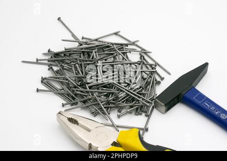 Metal nails, navy blue hammer, yellow pliers on a white background Stock Photo