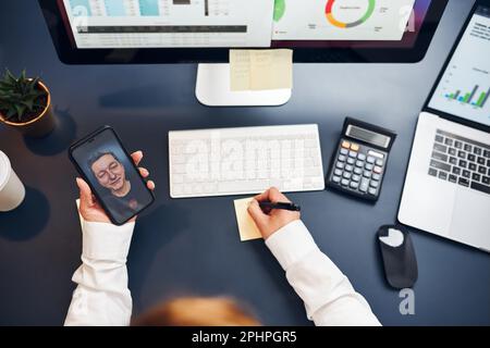 Woman entrepreneur having business video chat on smartphone. Businesswoman working with data on charts, graphs and diagrams on computer screen. Woman Stock Photo