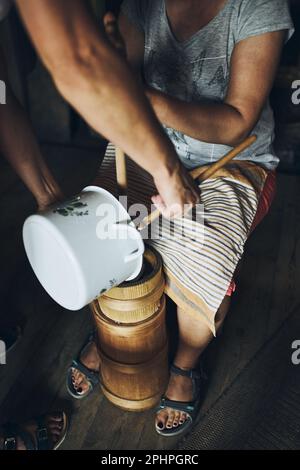 Woman making butter with butter churn. Old traditional method making of butter Stock Photo