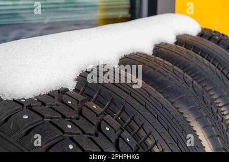 Winter tires covered by snow. Studded and friction tires. Stock Photo