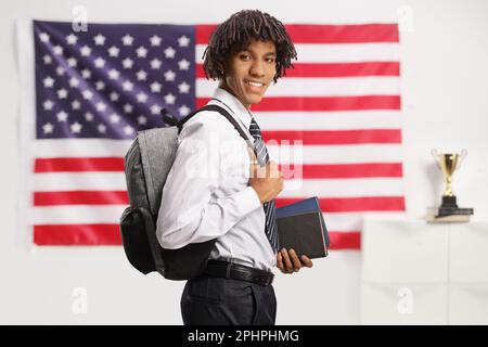 African american male student carrying a backpack and posing with USA flag in the background Stock Photo