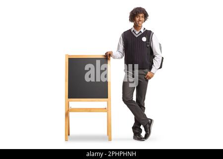 Full length portrait of a male african american student in a uniform leaning on blackboard isolated on white background Stock Photo
