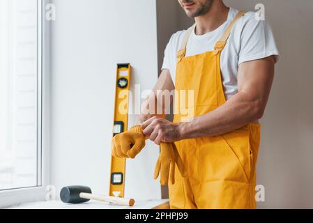 Handyman in yellow uniform preparing for work indoors. House renovation conception Stock Photo