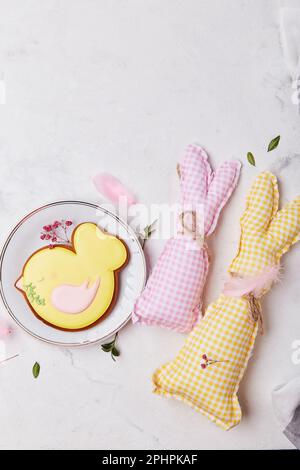 Hand made easter rabbit with yellow chicken cookie made of cotton and wool on white wooden table. Stock Photo