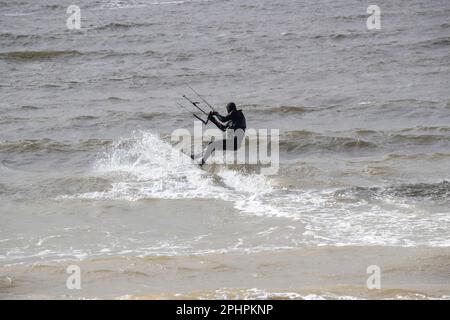 Kitesurfer enjoying the thrills of surfing on choppy and wavy water on the West shore of Llandudno in windy conditions Stock Photo