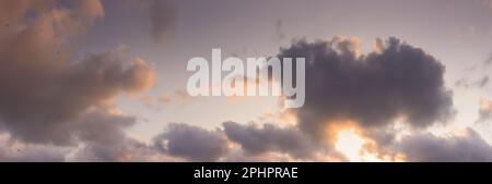 panorama of a sky in warm evening light. massive clouds in orange color at sunset Stock Photo