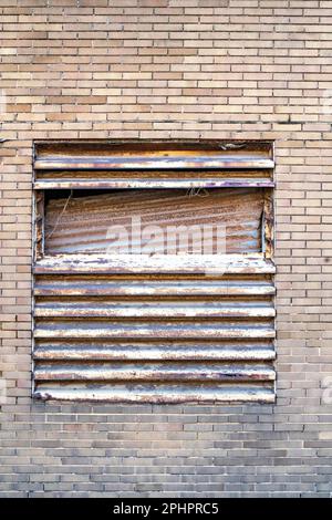 Old Louvre shutters to window of commercial building Stock Photo