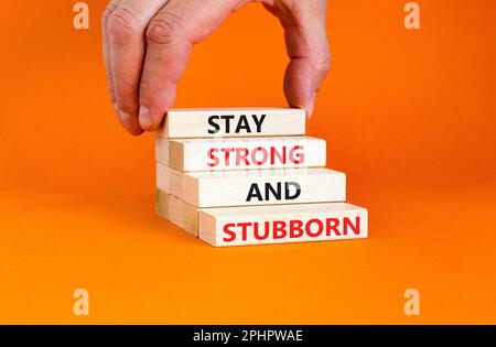 Stay strong and stubborn symbol. Concept words Stay strong and stubborn on wooden block. Beautiful orange table orange background. Motivational busine Stock Photo