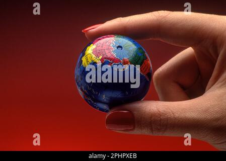 1991 HISTORICAL WOMAN’S HAND HOLDING TOY PLANET EARTH GLOBE Stock Photo