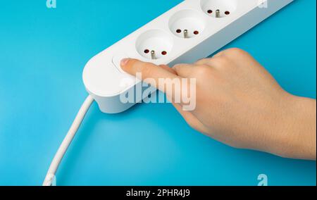 Turning on Electricity on Power Strip, Extension Cable, Electricity Strip, Home Socket, Power Extender, Extension Cord on Blue Background Stock Photo
