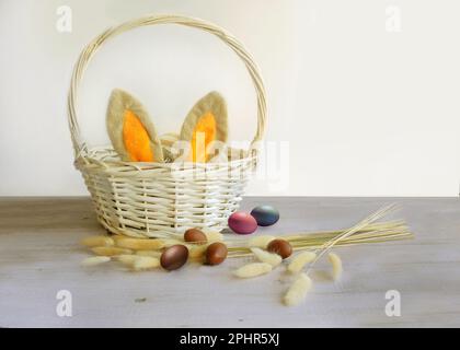 easter eggs and a white basket with rabbit ears Stock Photo