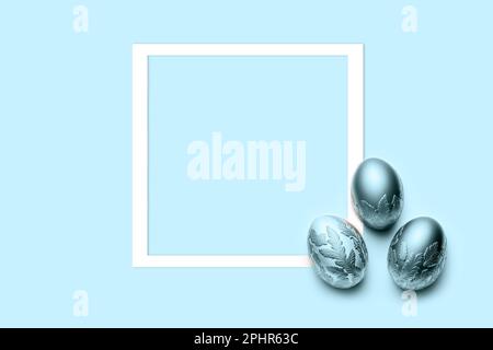three blue eggs with frame on blue background. Flat lay, top view, copy space. Stock Photo