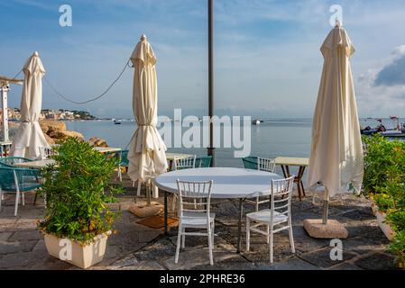 Table and chair on the waterfront of Porto d'Ischia town at Ischia island, Italy. Stock Photo