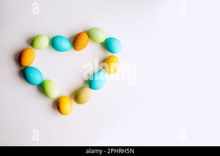 Easter bright, colored eggs in the shape of a heart lie on an isolated white background. The concept of kindness, faith in the holiday. Greeting card Stock Photo