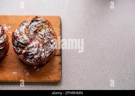 Easter Kraffin on light wooden background. Cake with candied fruits, raisins, chocolate, nuts, topping with powdered sugar, edible decorations. Rustic Stock Photo