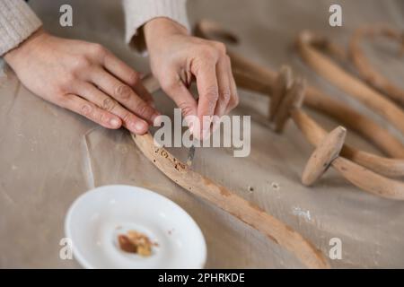 Close up of craftsman hand repairing cracks on old-fashioned piece of furniture in workshop Stock Photo