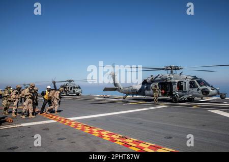 230221-N-YD731-1149 ADRIATIC SEA (Feb. 21, 2023) Naval Air Crewman (Helicopter) 2nd Class Jake Rambow, right, assigned to Helicopter Sea Combat Squadron (HSC) 5, loads Spanish Marines into an MH-60S Nighthawk helicopter aboard Spanish Navy Ship ESPS Juan Carlos I (LHD 61), Feb. 21, 2023. Carrier Air Wing (CVW) 7 is the offensive air and strike component of Carrier Strike Group (CSG) 10 and the George H.W. Bush CSG. The squadrons of CVW-7 are Strike Fighter Squadron (VFA) 143, VFA-103, VFA-86, VFA-136, Carrier Airborne Early Warning Squadron (VAW) 121, Electronic Attack Squadron (VAQ) 140, Heli Stock Photo