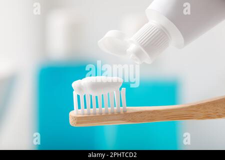 Applying toothpaste on brush against blurred background, closeup Stock Photo