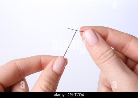 Woman threading sewing needle on white background, closeup Stock Photo