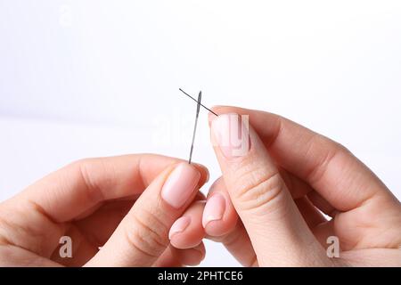Woman threading sewing needle on white background, closeup Stock Photo
