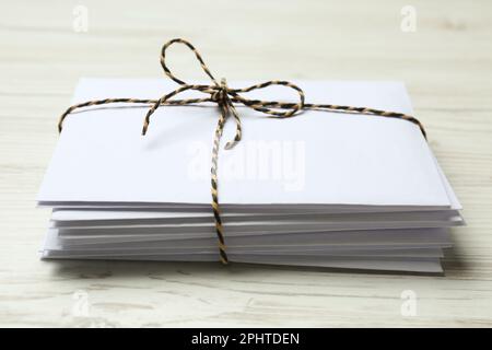 Stack of letters tied with string on white wooden table, closeup Stock Photo