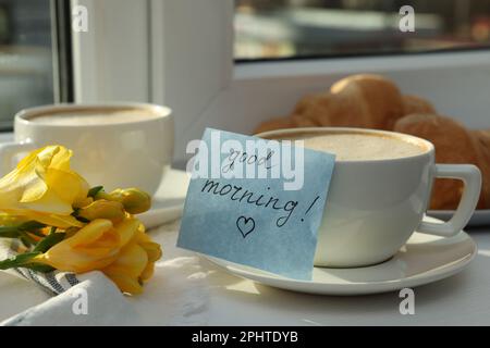 Coffee, flowers and card with phrase GOOD MORNING! near window Stock Photo