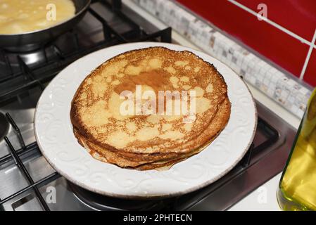 Plate of freshly made crepes on stove in kitchen Stock Photo