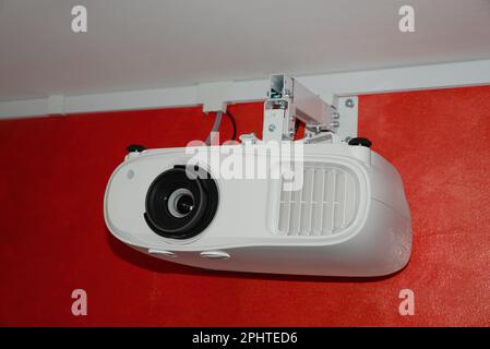 Modern digital video projector on red wall indoors Stock Photo