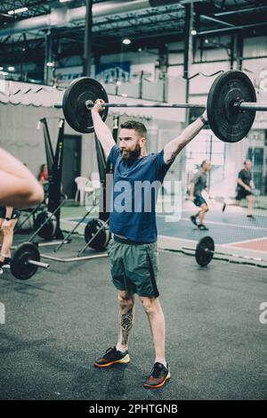 young handsome bearded sportsman lifting barbell at modern fitness center gym crossfit Stock Photo