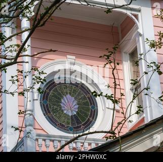 NEW ORLEANS, LA, USA - MARCH 8, 2023: Elaborate stained glass window backing a balcony on a pink historic house with white trim