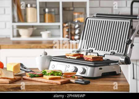 Modern electric grill with sandwiches on kitchen counter Stock Photo