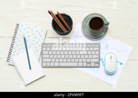 Composition with keyboard, coffee and blank notepad on light wooden background Stock Photo