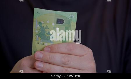 Close-up of male hands holding a pack of brand new crispy one hundred euro banknotes. A man rejoices in his profit from the sale by counting the money Stock Photo