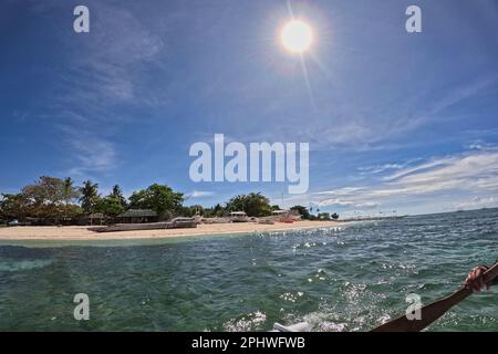 Idyllic view of Pamilacan Island in the Philippines and its beach with palm trees, taken on the sea from a wooden boat. Stock Photo