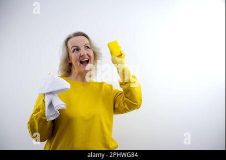 Beautiful young housewife cleaning blank space wearing apron and gloves isolated on white. High quality photo Stock Photo