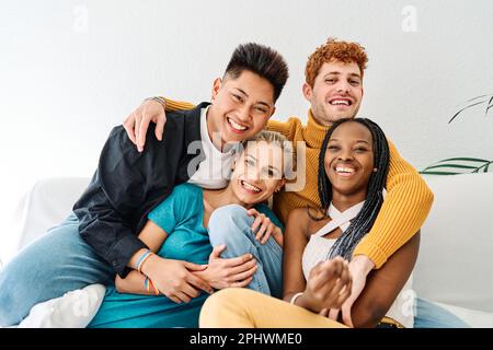 Multiethnic group of friends embracing at the sofa and smiling Stock Photo