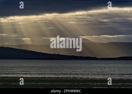Sun rays crepuscular rays breaking through cloudy sky at Bruny Island, Tasmania, Australia Stock Photo