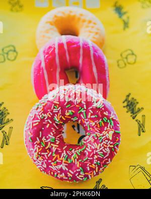 The three glazed donuts on a yellow table cloth. Stock Photo