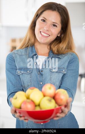 happy woman offering apple to the camera Stock Photo