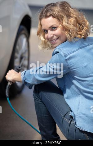 frustrated female driver with tyre iron trying to change wheel Stock Photo