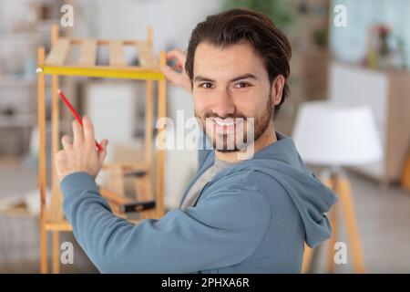 man putting up wooden shelf at home Stock Photo