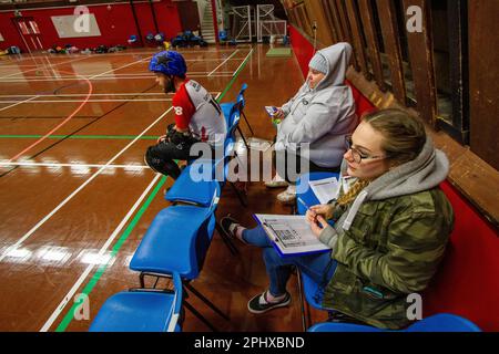 Non Skating Officials (NSOs) manage a roller derby penalty box where penalised skaters have to wait off track to serve out there penalty Stock Photo