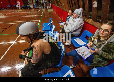 Non Skating Officials (NSOs) manage a roller derby penalty box where penalised skaters have to wait off track to serve out there penalty Stock Photo